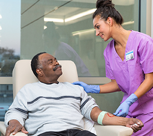 Healthcare provider preparing to take blood from man's arm.